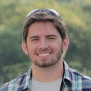 Photo de Bernard Legros, un homme avec une légère barbe brune et des cheveux mi-long brun. Il a une chemise à carreau.